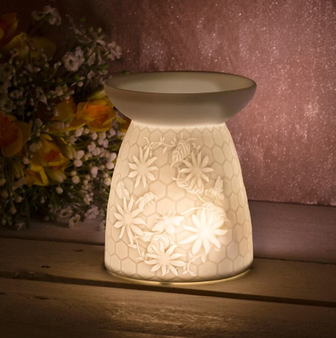 Glowing cream floral burner against a pink background