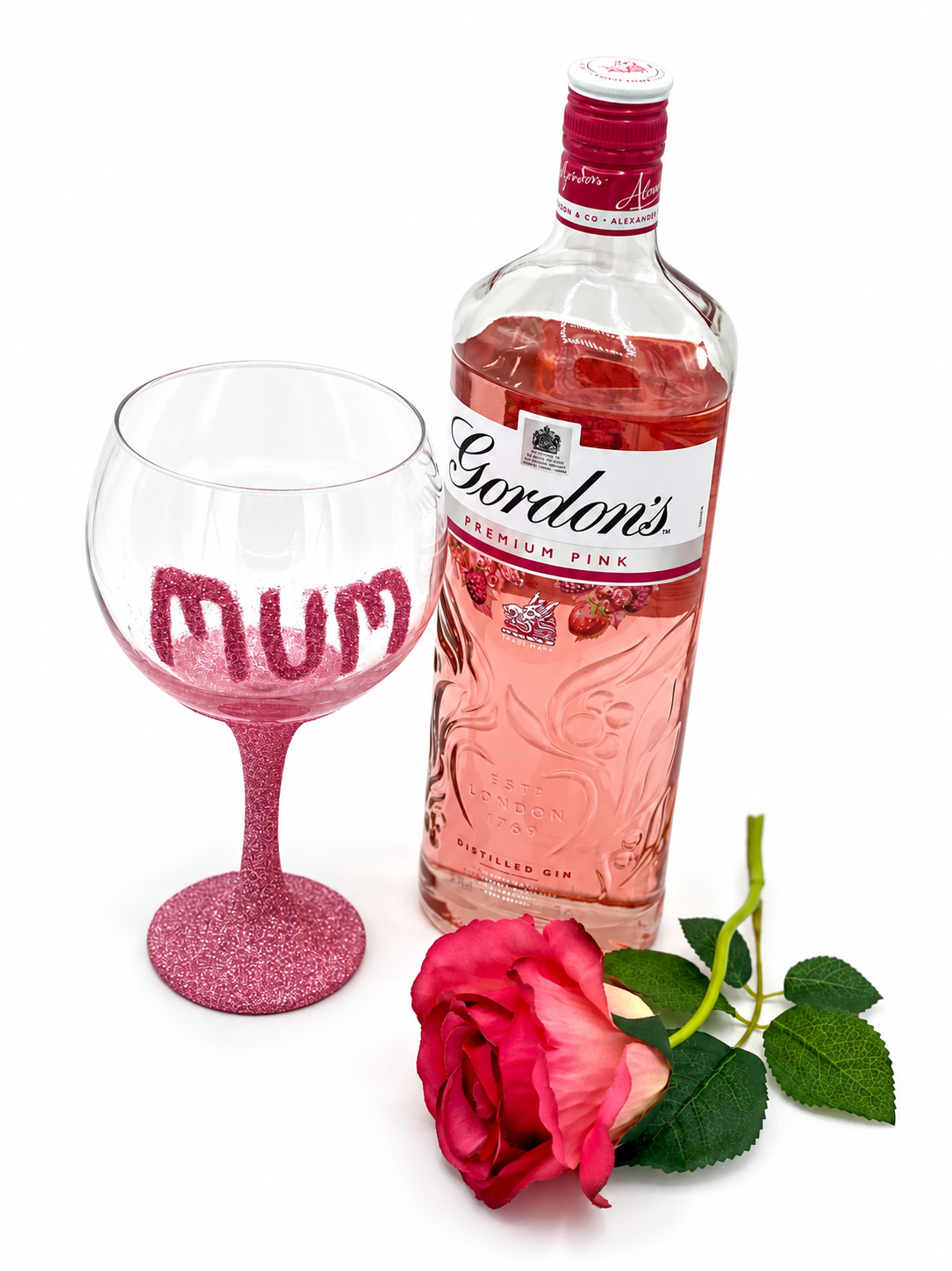 Pink glitter Mum gin glass, pink gin bottle and rose on white with soft shadows