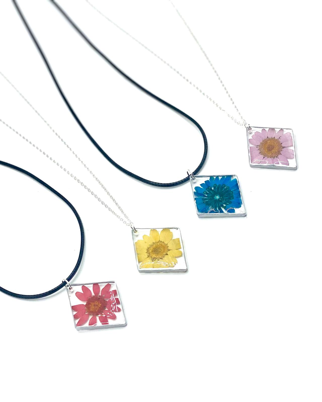 Four resin flower pendants in pink, blue, yellow and red